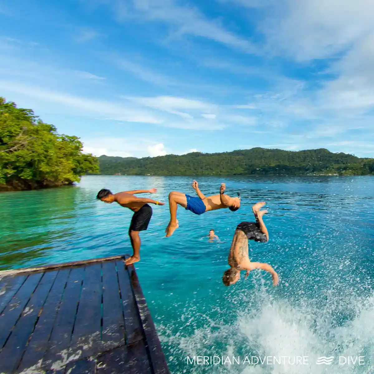 Guests jumping from an Arborek jetty into clear Raja Ampat water